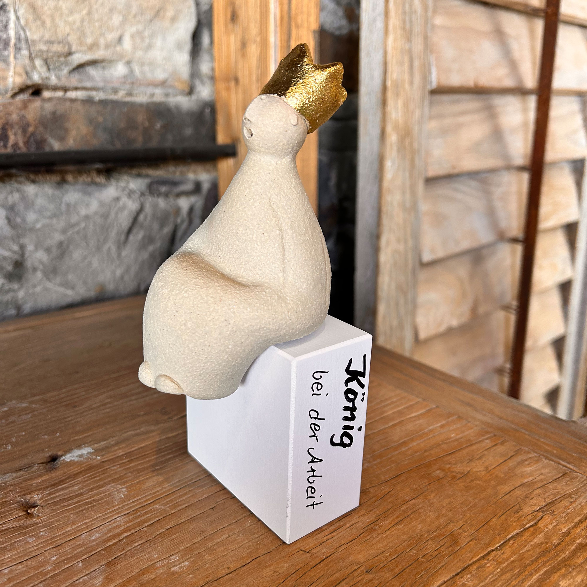 König sitzend auf weissem Holzsockel
